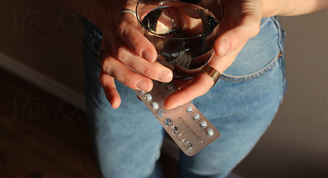 A woman holding abortion pills (Plan C) and a drink. A woman holding abortion pills (Plan C) and a drink.